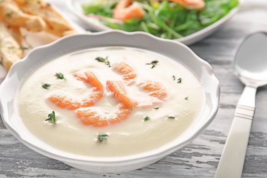 Tasty cream soup with fresh shrimps in bowl on table