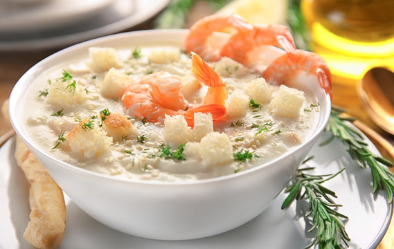 Tasty cream soup with fresh shrimps and croutons in bowl on table, closeup