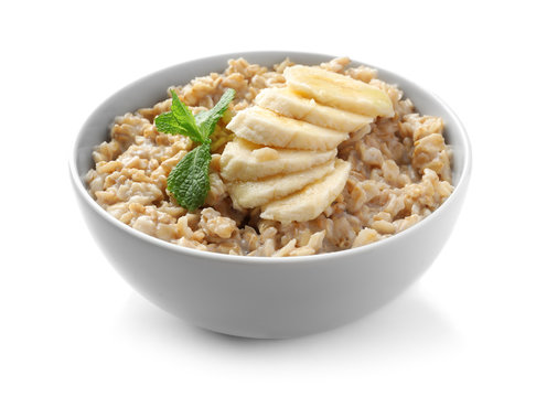Bowl with yummy oatmeal and banana against white background