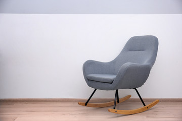 Grey rocking chair near light wall