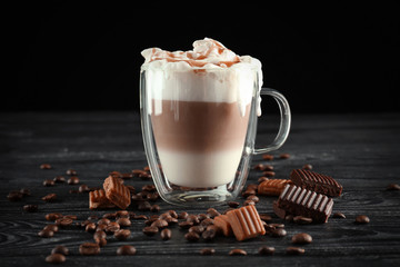Glass cup with caramel macchiato on table against black background