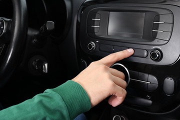 Man tuning radio in car