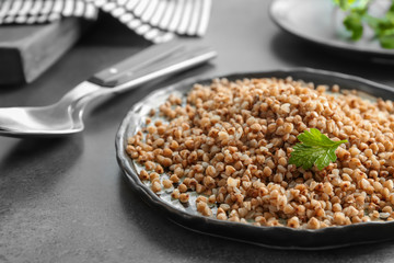 Plate with cooked buckwheat on table