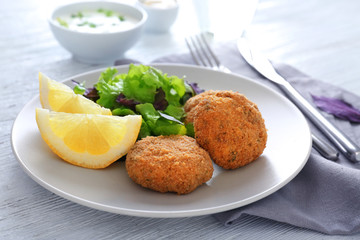 Plate with tasty salmon patties on table