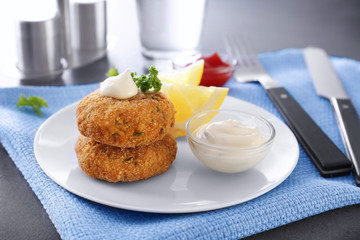 Plate with tasty salmon patties on table
