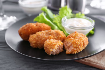 Plate with tasty salmon croquettes on table
