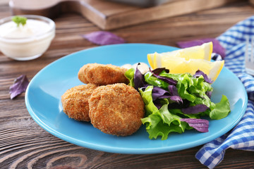 Plate with tasty salmon patties on table
