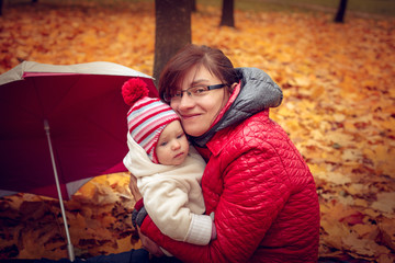 Mom with a child playing in autumn park.