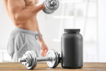 Dumbbell and jar with protein powder on table