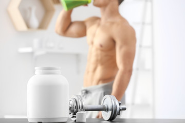Dumbbell and jar with protein powder on table