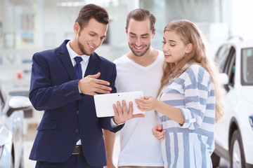 Car salesman and young couple in dealership
