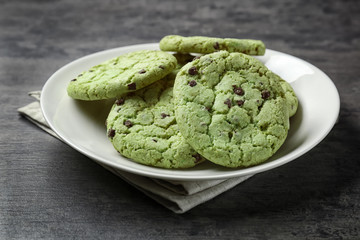Plate with mint chocolate chip cookies on grey background