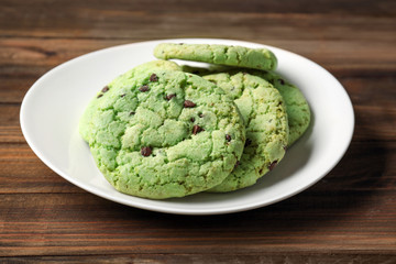 Plate with mint chocolate chip cookies on wooden table