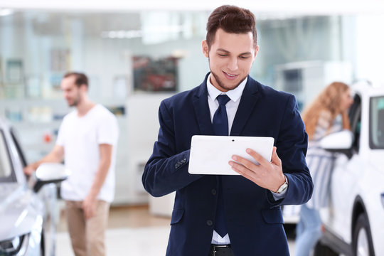 Car Salesman With Tablet In Dealership