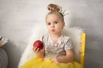 Adorable little girl eating apple indoors