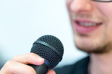 Junger Mann mit Mikrofon, Vortrag