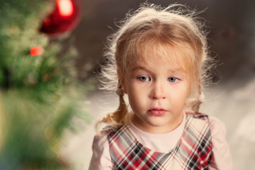 Pretty little child near Christmas tree.