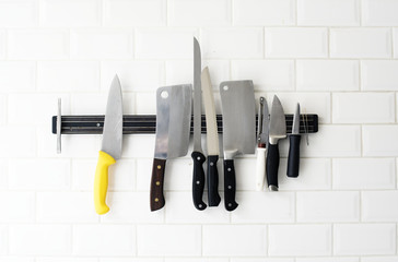 Set of knives hanging on the white wall - Powered by Adobe
