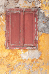 Old dark red wooden window on concrete broken textured house wall