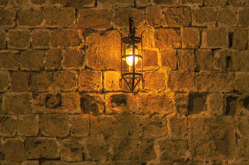 Old light at night hanging on a medieval street fortress wall background