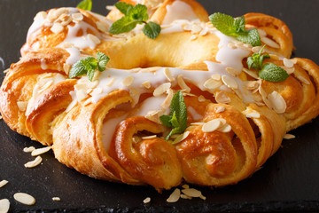 Sweet round brioche with sugar icing and almonds close-up. horizontal