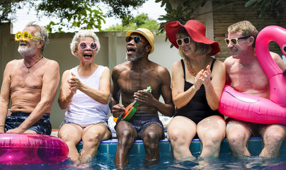 Group of diverse senior adults sitting by the pool enjoying summer together - Powered by Adobe