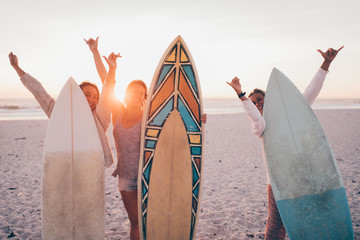 Group of young adult friends cheerful at beach with surfboards