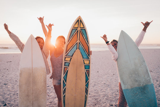 Group of young adult friends cheerful at beach with surfboards