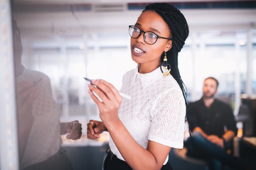 Young african businesswoman writing notes on whiteboard