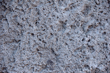 Background porous stone structure of volcanic origin from crater of an extinct volcano, gray color.