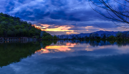 Rural lake landscape with wildlife, ducks and snow capped mountains in background with blue skies and clouds midst of fall foliage. 