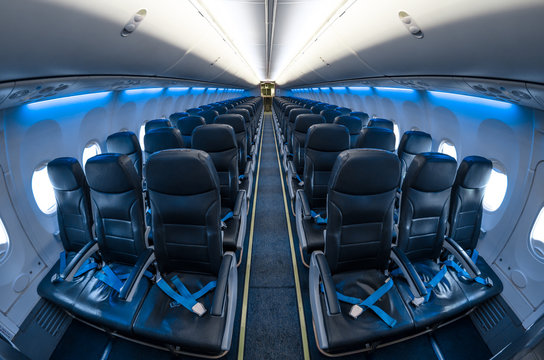 View of passenger seats in a blue-lit aircraft.