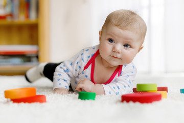 Cute baby girl playing with colorful wooden rattle toy