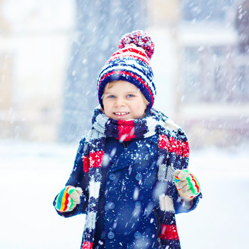 Happy kid boy having fun with snow in winter
