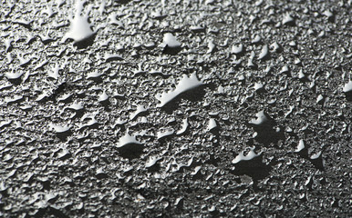 Abstract background of water drops on black slate surface.