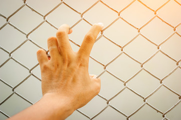 Hand holding on chain link fence, Vintage filter effect