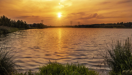 A lake at sunset on lovely midsummer evening with some electricity poles in the background