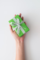 Woman hand holding green gift box isolated on white background. Top view, flat lay. Copyspace.