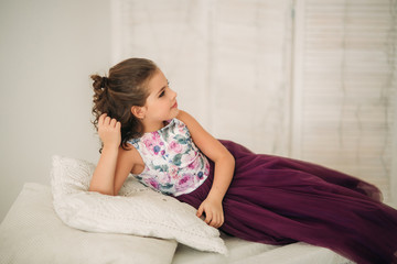 Beautiful girl in a purple dress and flower blouse posing for a photographer.