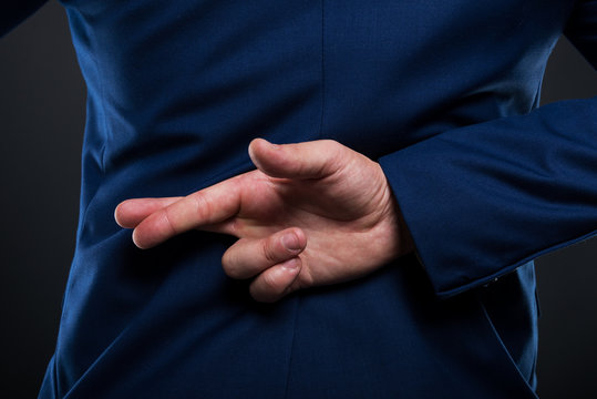 Closeup view of businessman standing with crossed fingers - Powered by Adobe