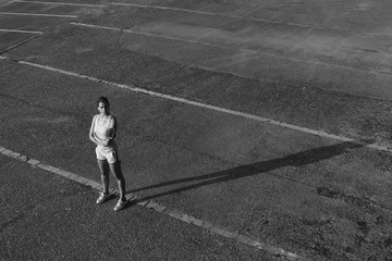 Motivated female athlete listening music and taking a break for resting after running on asphalt.