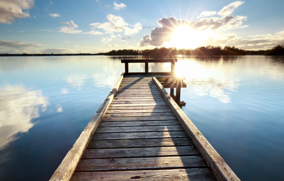 gold sunshine over wooden pier on big lake