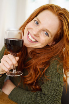 lächelnde frau hält ein glas rotwein in der hand