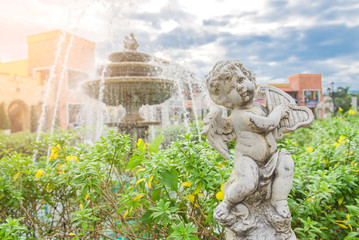 Cute little child sculpture decorate in front of fountain in the garden .