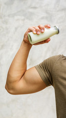 Man holding a bottle of milk on gray background.