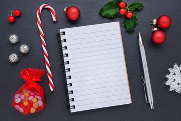 christmas decoration with a blank notebook and holly berries on black