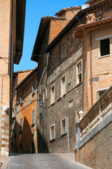 Fototapeta na wymiar Urbino, Italy - August 9, 2017: A small street in the old town of Urbino. sunny day.