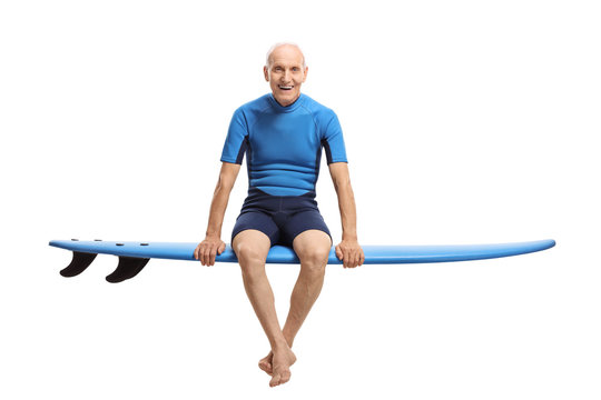 Elderly surfer sitting on a surfboard and smiling