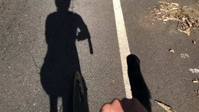 Cyclist pedaling. Shadow of a cyclist on the road. Point of view.