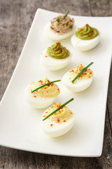 Variety of stuffed eggs with avocado and tuna on wooden table